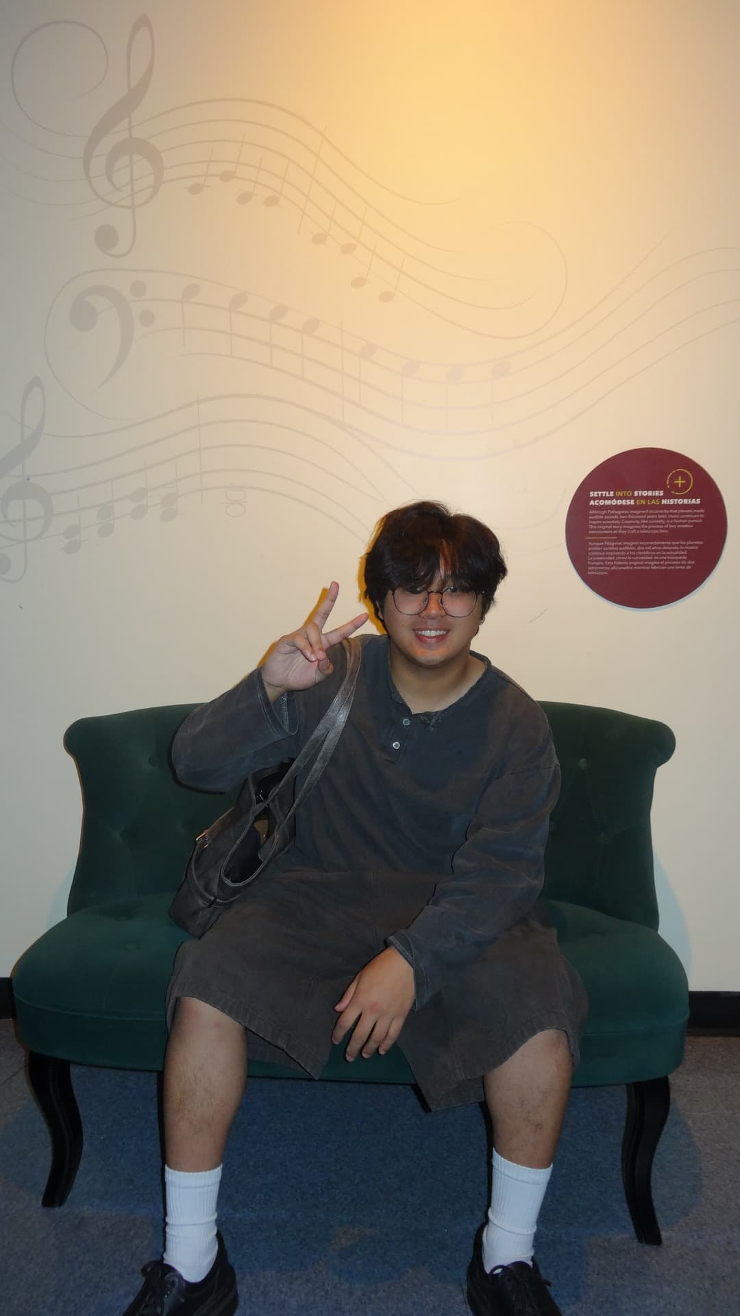 Joshua sitting on a couch, throwing up a peace sign